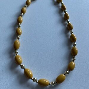 Maybe Bakelite. Mustard color vintage necklace. Gold tone accents.